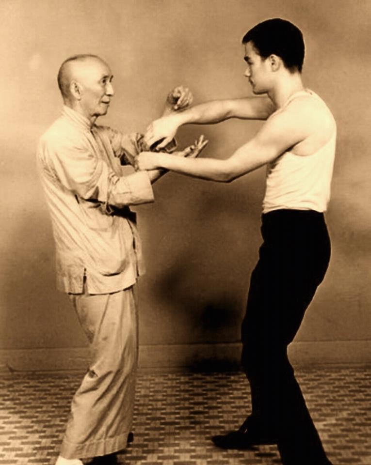 Grandmaster Ip Man practicing chi sau with a young Bruce Lee.